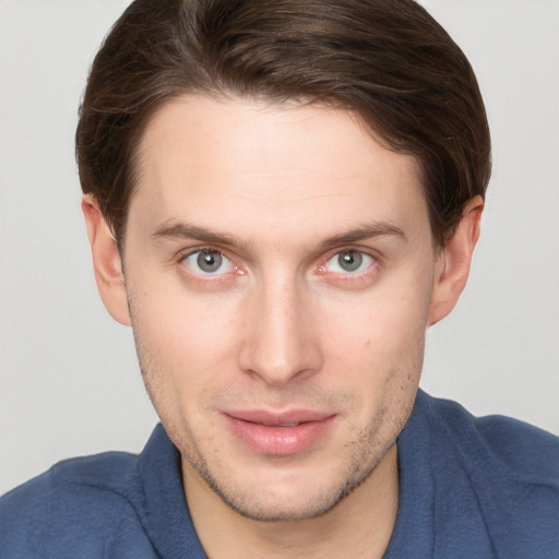 Joyful white young-adult male with short  brown hair and grey eyes