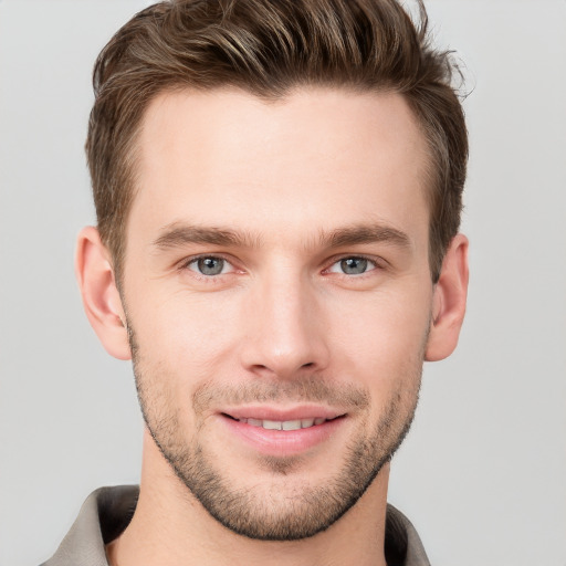 Joyful white young-adult male with short  brown hair and grey eyes