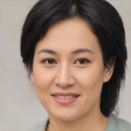 Joyful asian adult female with medium  brown hair and brown eyes