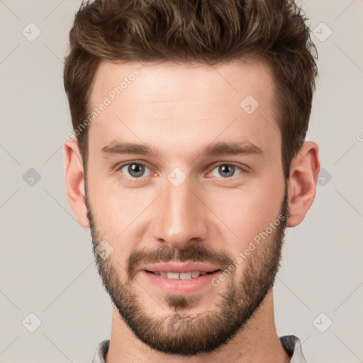 Joyful white young-adult male with short  brown hair and grey eyes