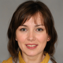 Joyful white young-adult female with medium  brown hair and blue eyes