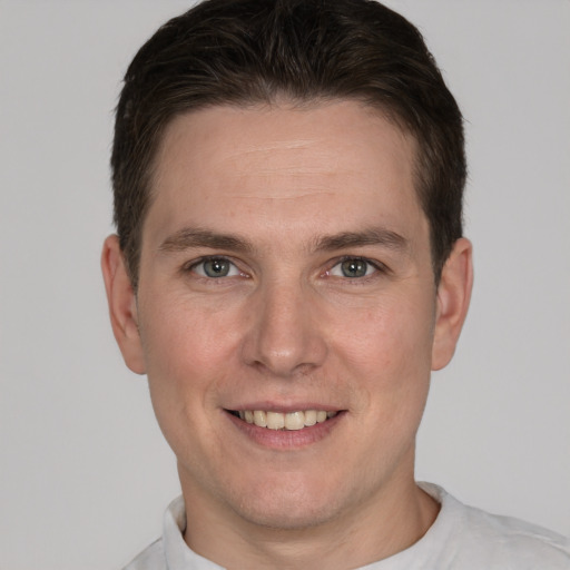 Joyful white young-adult male with short  brown hair and grey eyes