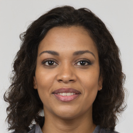 Joyful black young-adult female with long  brown hair and brown eyes