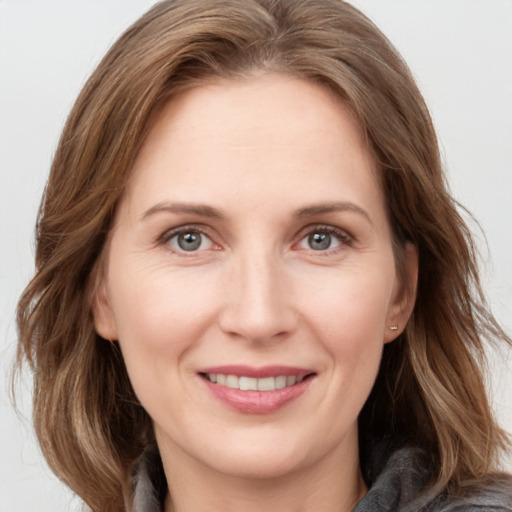 Joyful white young-adult female with medium  brown hair and grey eyes