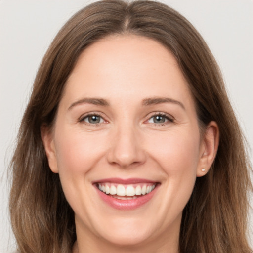 Joyful white adult female with long  brown hair and grey eyes