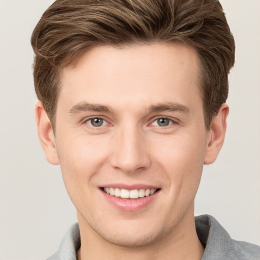 Joyful white young-adult male with short  brown hair and grey eyes