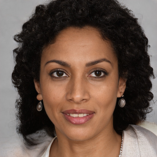 Joyful black young-adult female with long  brown hair and brown eyes