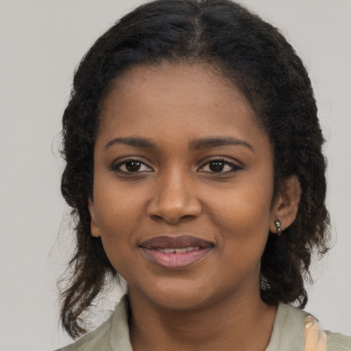 Joyful black young-adult female with long  brown hair and brown eyes