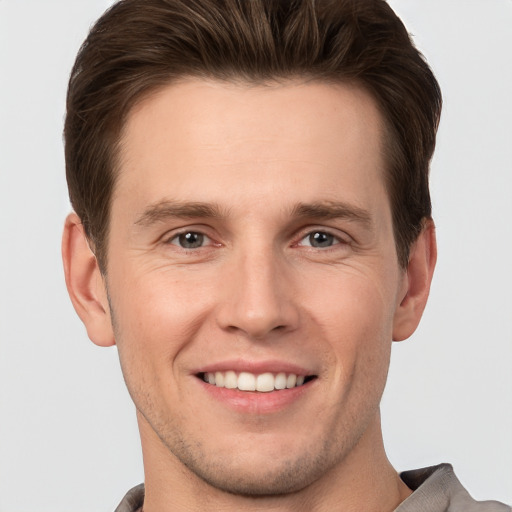 Joyful white young-adult male with short  brown hair and grey eyes