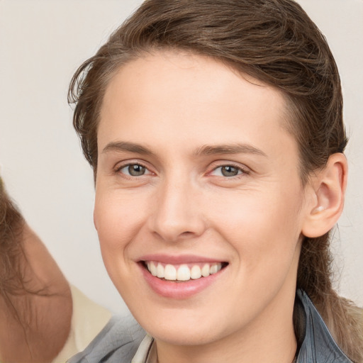 Joyful white young-adult female with medium  brown hair and grey eyes