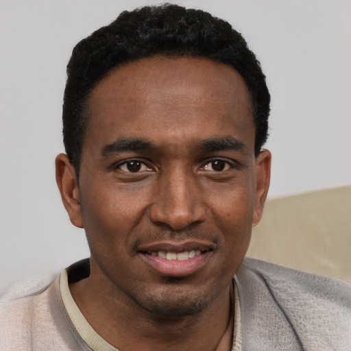 Joyful black young-adult male with short  black hair and brown eyes