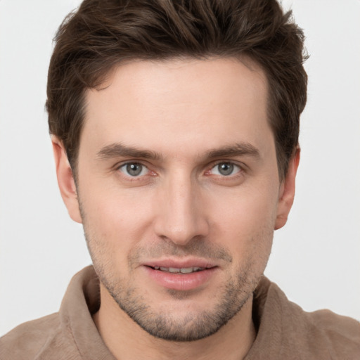 Joyful white young-adult male with short  brown hair and grey eyes