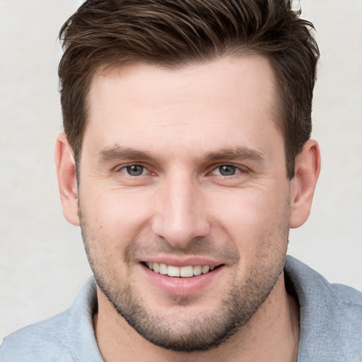 Joyful white young-adult male with short  brown hair and grey eyes