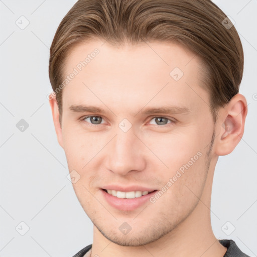 Joyful white young-adult male with short  brown hair and grey eyes