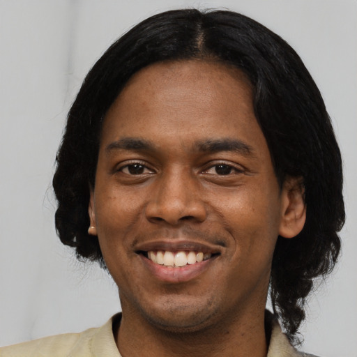 Joyful black young-adult male with medium  black hair and brown eyes