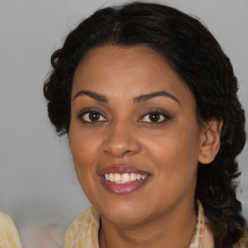 Joyful black adult female with long  brown hair and brown eyes