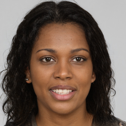 Joyful black young-adult female with long  brown hair and brown eyes
