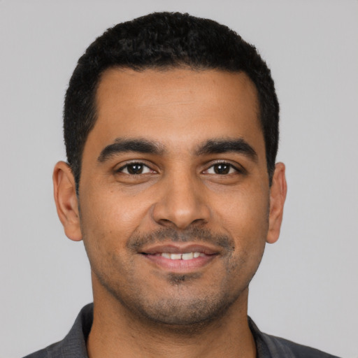 Joyful latino young-adult male with short  black hair and brown eyes