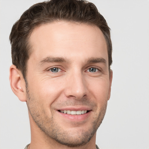 Joyful white young-adult male with short  brown hair and grey eyes