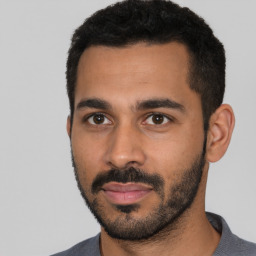 Joyful latino young-adult male with short  black hair and brown eyes