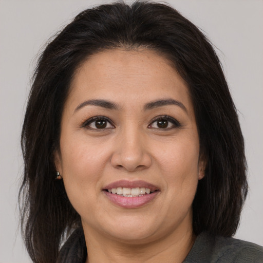 Joyful latino adult female with medium  brown hair and brown eyes