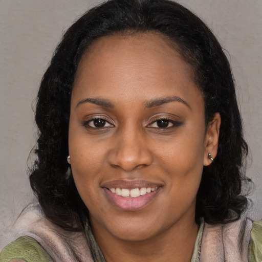 Joyful black young-adult female with long  black hair and brown eyes