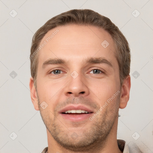 Joyful white young-adult male with short  brown hair and grey eyes