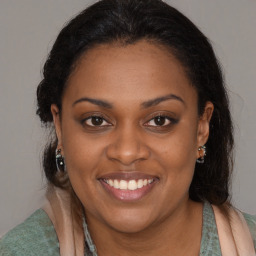 Joyful black young-adult female with long  brown hair and brown eyes