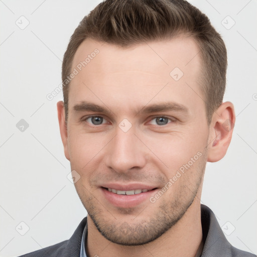 Joyful white young-adult male with short  brown hair and grey eyes