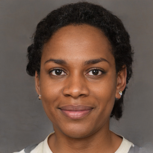 Joyful black young-adult female with short  black hair and brown eyes