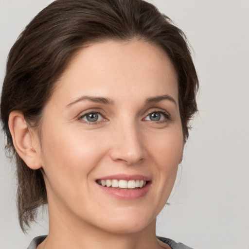 Joyful white young-adult female with medium  brown hair and grey eyes