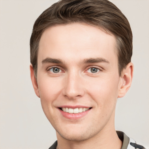 Joyful white young-adult male with short  brown hair and grey eyes