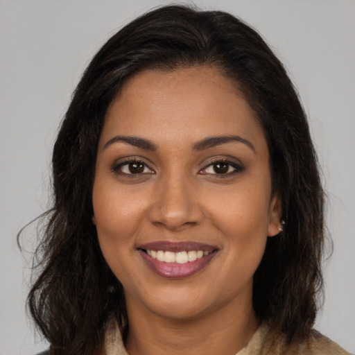 Joyful black young-adult female with long  brown hair and brown eyes