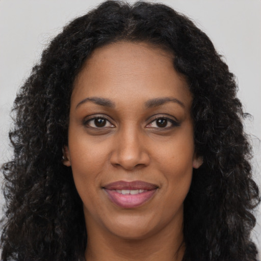Joyful black young-adult female with long  brown hair and brown eyes
