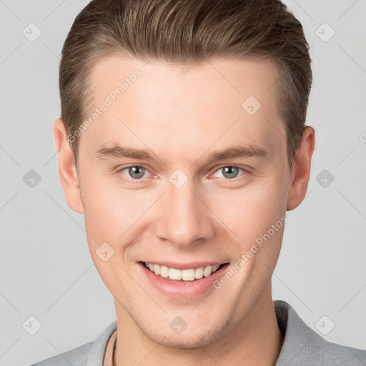 Joyful white young-adult male with short  brown hair and grey eyes