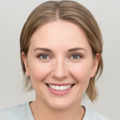 Joyful white young-adult female with medium  brown hair and grey eyes