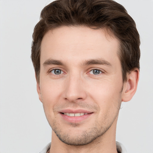 Joyful white young-adult male with short  brown hair and grey eyes