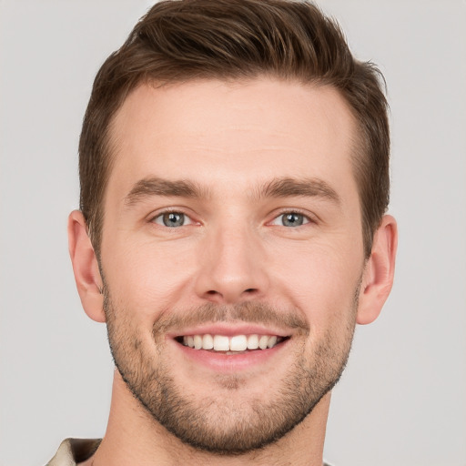 Joyful white young-adult male with short  brown hair and grey eyes