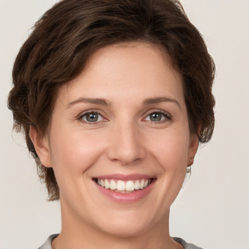 Joyful white young-adult female with short  brown hair and grey eyes