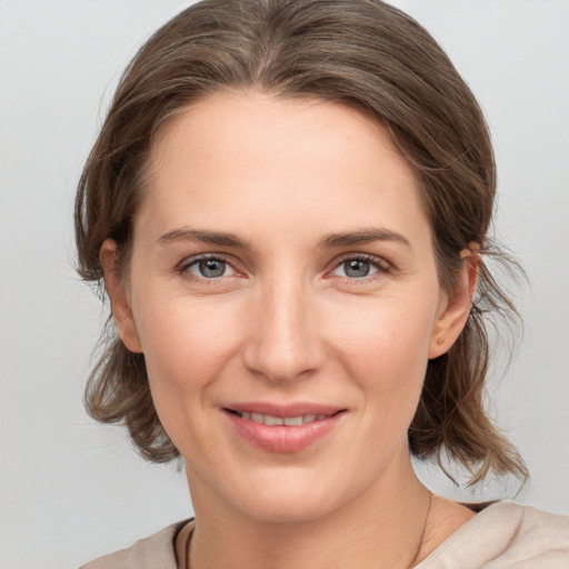 Joyful white young-adult female with medium  brown hair and grey eyes