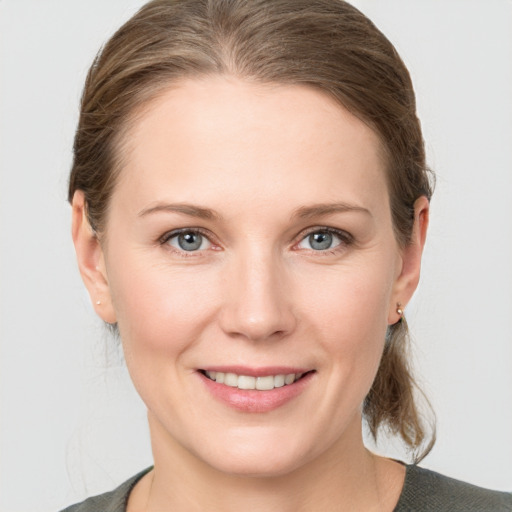 Joyful white young-adult female with medium  brown hair and grey eyes