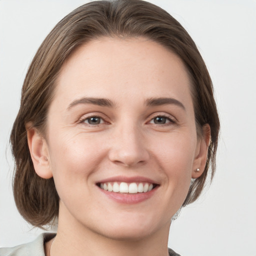 Joyful white young-adult female with medium  brown hair and grey eyes