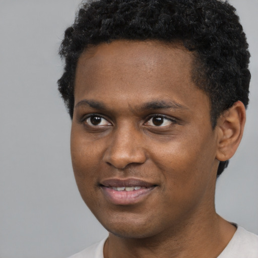 Joyful black young-adult male with short  black hair and brown eyes