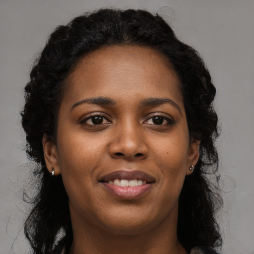Joyful black young-adult female with long  black hair and brown eyes
