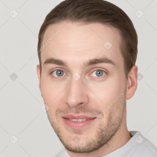 Joyful white young-adult male with short  brown hair and grey eyes