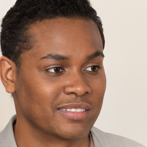 Joyful black young-adult male with short  brown hair and brown eyes