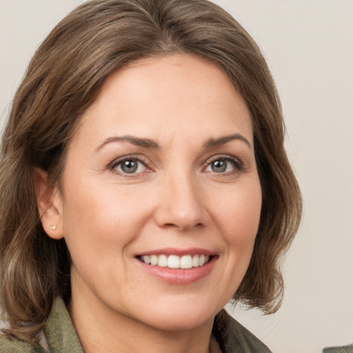 Joyful white adult female with medium  brown hair and green eyes