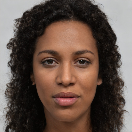 Joyful black young-adult female with long  brown hair and brown eyes
