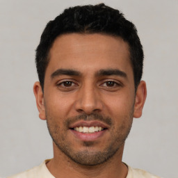 Joyful latino young-adult male with short  black hair and brown eyes