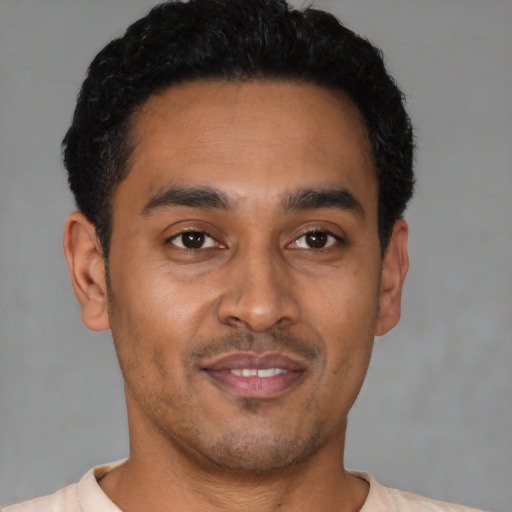 Joyful latino young-adult male with short  black hair and brown eyes